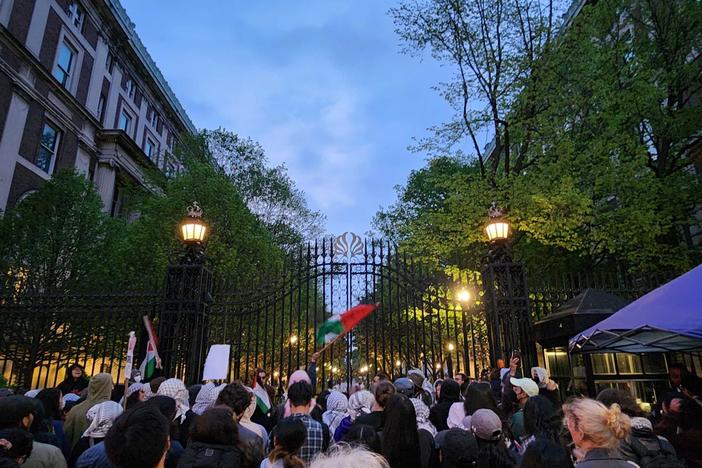A crowd gathers Tuesday evening by the gates in front of Columbia University's Hamilton Hall.
