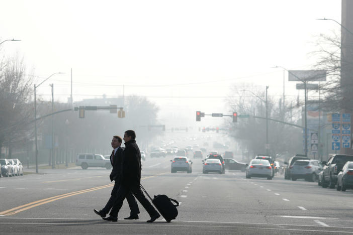 Men cross the street in smog filled downtown Salt Lake City, Utah, U.S. December 12, 2017. Sometimes during the winter, temperature inversions form in the Salt Lake Valley, when the upper air temperature is warmer than the air on the valley floor, forming a lid, trapping polluted air. REUTERS/George Frey