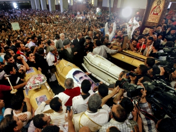 Egyptian Christians gather around four coffins during a funeral service at the Saint Mark Coptic cathedral in Cairo on April 7. Religious violence this month has killed three Muslims and at least six Christians.