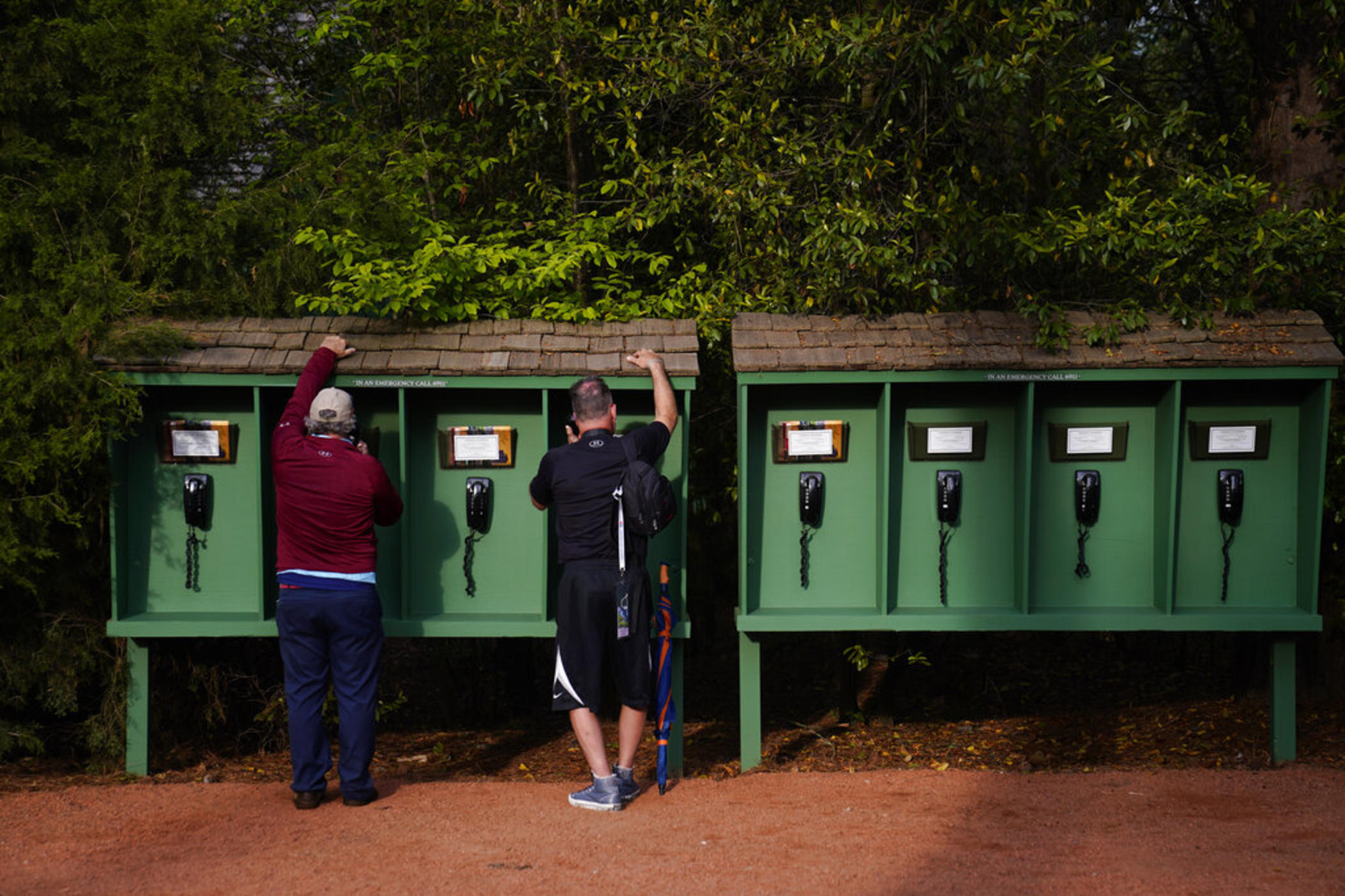 With mobile phones prohibited on the Augusta National Golf Course, spectators use phones provided by the club near the seventh hole during a practice round for the Masters golf tournament on Tuesday, April 5, 2022, in Augusta, Ga.
