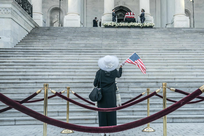 Woman waves flag outside US Capitol where Casket of John Lewis is on display