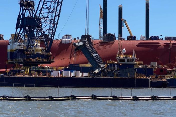 A salvage crew used a crane on June 24 to hoist a section of the Golden Ray's ramp used to load vehicles on and off the ship. The Coast Guard is delaying the ship’s removal from St. Simons Sound until at least October to avoid the peak of hurricane season.