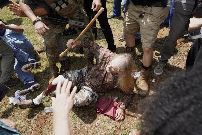 A man falls after being hit by counter demonstrators during a protest , Saturday, Aug. 15, 2020, in Stone Mountain Village, Ga. Several dozen people waving Confederate flags, many of them wearing military gear, gathered in downtown Stone Mountain where they faced off against a few hundred counterprotesters, many of whom wore shirts or carried signs expressing support for the Black Lives Matter movement. 