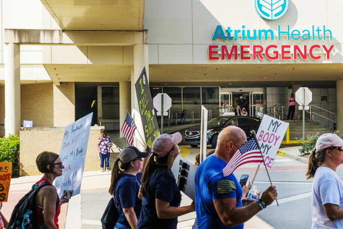 Protesters against the vaccine mandate for employees of the Medical Center at Atrium Health in Macon march by the hospital emergency room entrance on Saturday, August 14. Only a fraction of the about 100 protesters were Medical Center employees. 