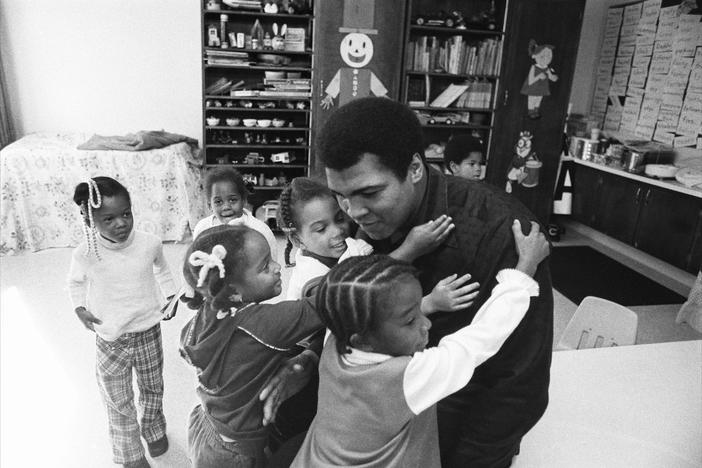 Muhammad Ali hugging a group of small girls.