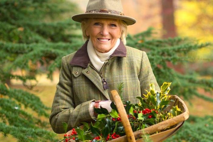 Mary Berry holding a basket of holly outdoors.