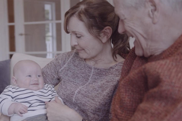 A couple hold their smiling grandchild.