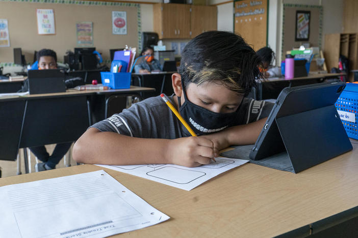 Student with mask sits at desk