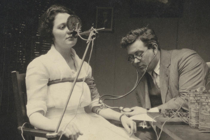 A man using a polygraph on a seated woman.