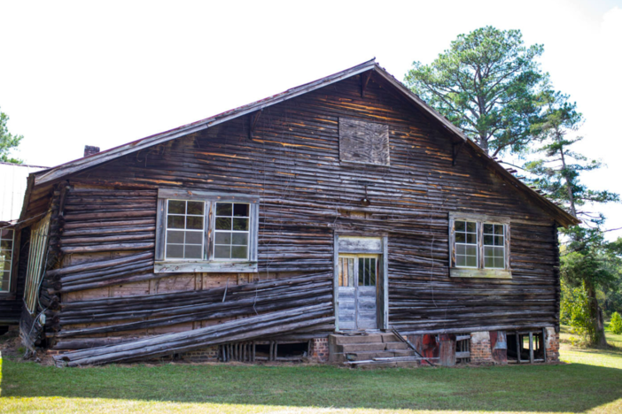 An old log cabin is shown in this daytime photo.