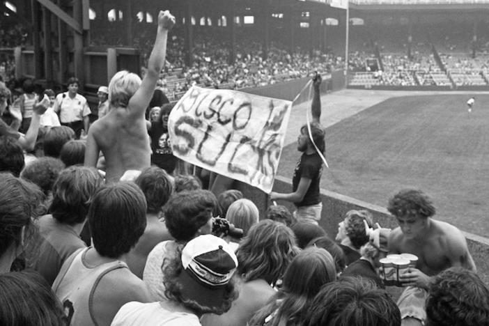 A black and white photo of the crowd at a baseball game holding a sign that says "Disco Sucks."