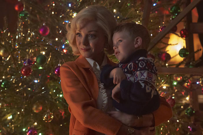 Trixie from Call the Midwife holding a child in front of a Christmas tree.