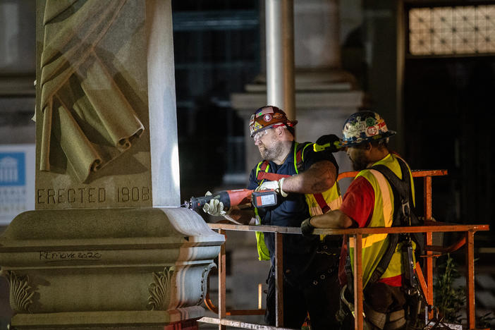 Workers loosen the base of a Confederate monument Thursday, June 18, 2020, in Decatur, Ga. The 30-foot obelisk in Decatur Square, erected by the United Daughters of the Confederacy in 1908, was ordered by a judge to be removed placed into storage.