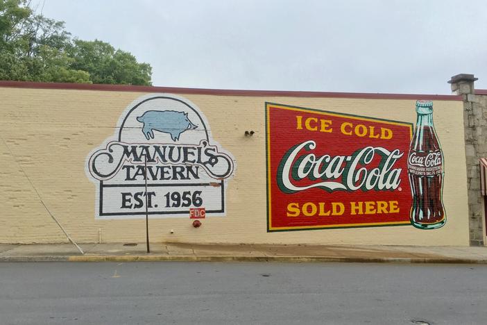 The newly-repainted signs advertising Manuel's Tavern and Coca-Cola.