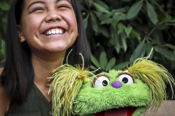 10-year-old Salia Woodbury pictured, whose parents are in recovery, with "Sesame Street" character Karli in New York. Sesame Workshop is addressing the issue of addiction.