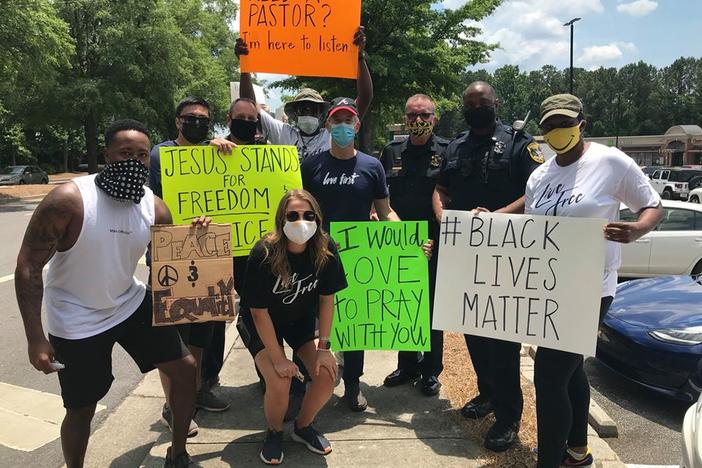 Protesters in pose for a picture with Dunwoody police officers after a protest in front of the police department's headquarters on June 1.