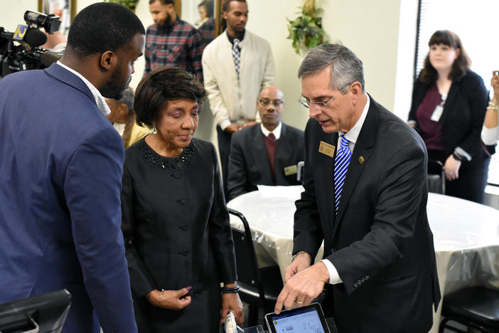 Rev. Bettye Holland Williams (center), president of the Concerned Black Clergy of Metro Atlanta, receives a demonstration of the new system from Secretary of State Brad Raffensperger and elections staff.