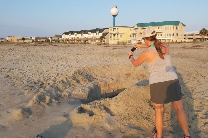 Tammy Smith of the Tybee Sea Turtle Project photographs a hole someone dug on the Tybee beach so she can warn people of the dangers such holes pose to sea turtles.
