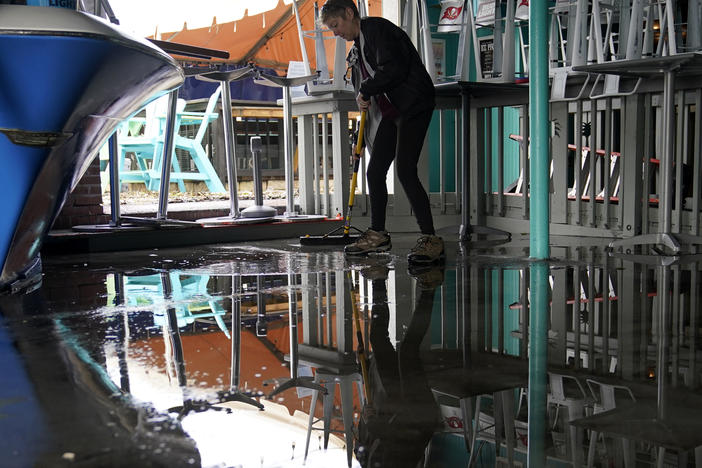 Kate Connell sweeps water and mud from the floor at Salty's Gulfport bar Thursday in Gulfport, Fla., in the aftermath of Tropical Storm Eta.