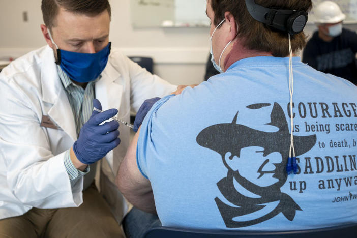 A pharmacist administers a dose of a COVID-19 vaccine to a worker at a processing plant in Arkansas City, Kan., on March 5. Researchers are concerned that vaccination rates in some rural communities may not keep up with urban rates.