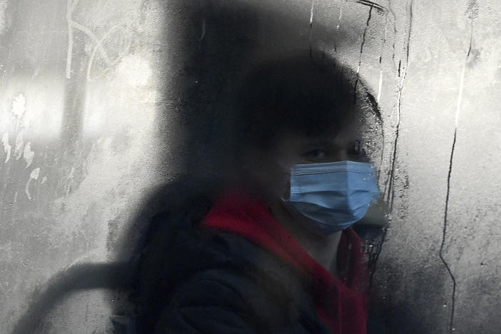 A commuter masks up for a bus ride in Liverpool, England. The omicron variant of the coronavirus has surged in the U.K. and is now dominant in the U.S. as well. There's now data indicating just how severe its symptoms might be.
