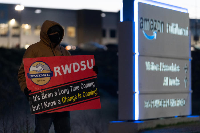 A retail union representative holds a sign by the Amazon warehouse in Bessemer, Ala., during the first union election in March 2021.
