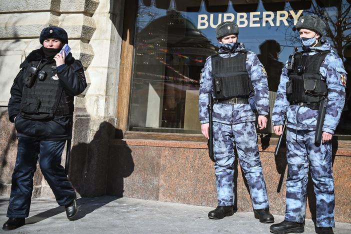 A Russian police officer and national guard servicemen patrol Red Square next to Burberry shop in Moscow on Thursday. The U.K. imposed a new export ban that will likely affect luxury vehicles, high-end fashion and works of art.