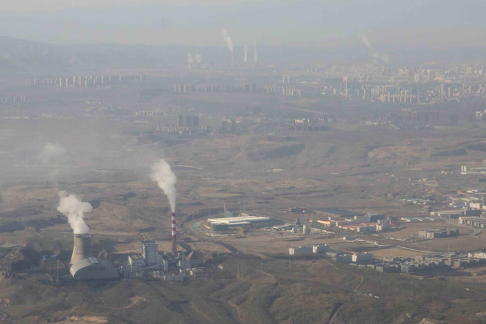 Smoke and steam rise from towers at the coal-fired Urumqi Thermal Power Plant as seen from a plane in Urumqi in western China's Xinjiang Uyghur Autonomous Region on April 21, 2021.