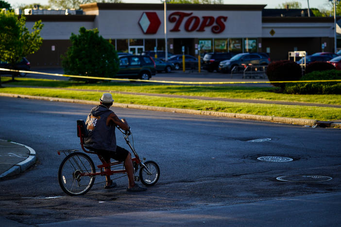 A cyclist pauses outside the site of the supermarket shooting in Buffalo, N.Y. With the Tops store closed for the foreseeable future, the community around it has been left without easy access to healthy and affordable food.