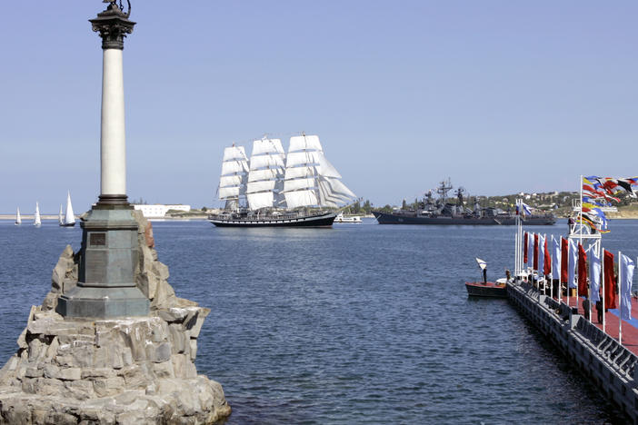 The Russian Black Sea naval headquarters at Sevastopol, Crimea, in 2008. In the background on the right is a Russian destroyer. The Russian tall ship Padalla (with white sails) is in the center. In the foreground is the Monument to Scuttled Ships, marking Russia's intentional destruction of its own naval fleet in the Crimean War in 1854 as British and French warships approached.