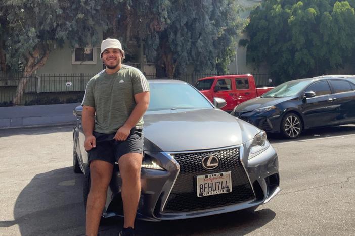 Johnny Navarro sits on the hood of his recently purchased 2014 Lexus.