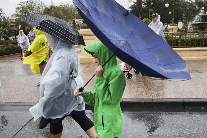 Winds blow an umbrella inside-out as guests leave the Magic Kingdom at Walt Disney World in Lake Buena Vista, Fla., Wednesday, Nov. 9, as conditions deteriorate with the approach of Hurricane Nicole.
