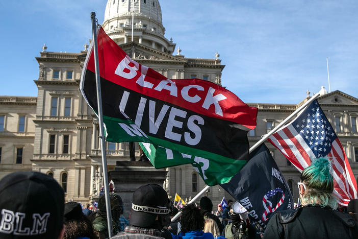 Counter-protesters carrying Black Lives Matter flags walk past a group of Trump supporters at the Michigan State Capitol building in November 2020 in Lansing, Mich.
