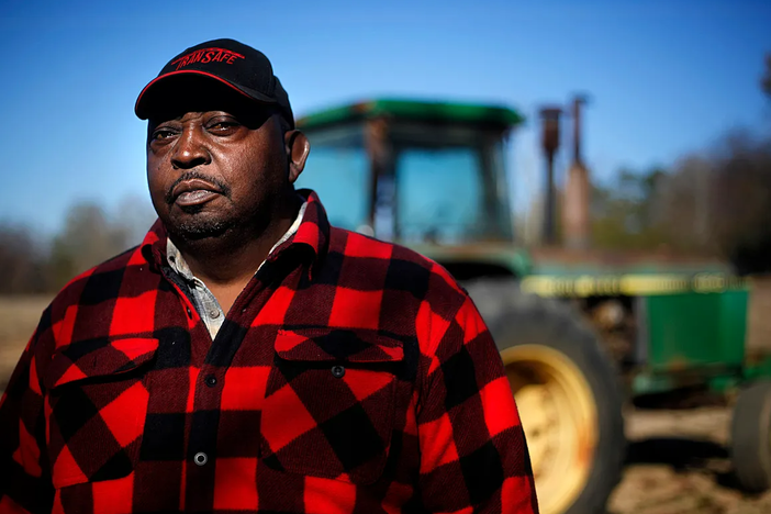 Lucious Abrams, a plaintiff in the Pigford v. Glickman class action lawsuit, stands in front of a tractor on his Georgia farm.