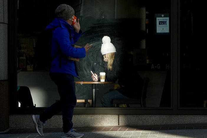 A woman is lit by sunlight Wednesday while sitting inside a coffee shop in San Francisco. A brutal winter storm knocked out power in California, closed interstate highways from Arizona to Wyoming and prompted more than 1,200 flight cancellations Wednesday — and the worst won't be over for several days.