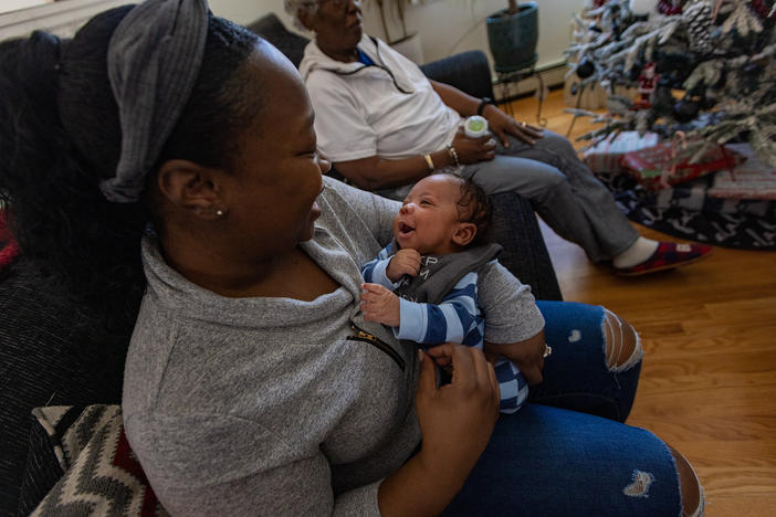 Kennise Nevers holds her son, AJ, in her arms at home. Nevers' mother, Nancy Josey, looks on.