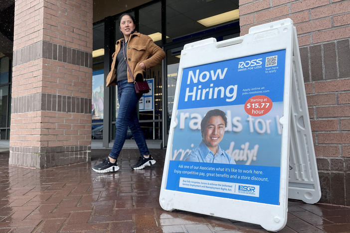 A customer walks by a "now hiring" sign posted in front of a store in Novato, Calif., on April 7, 2023.