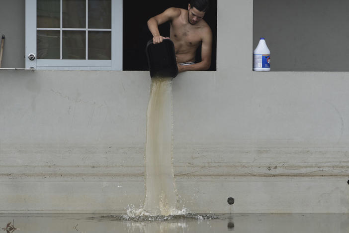A resident bails water from a flooded home in the aftermath of Hurricane Maria in Catano, Puerto Rico in 2017. Climate change is making hurricanes more dangerous.
