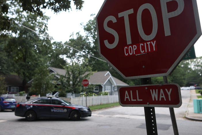 A police car drives through an intersection near Brownwood Park on Saturday where a stop sign has been modified in opposition to the Atlanta Public Safety Training Center that protesters refer to as "Cop City," in Atlanta.