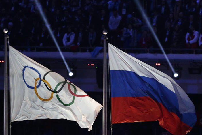 The Russian national flag, right, flies after it is hoisted next to the Olympic flag during the closing ceremony of the 2014 Winter Olympics in Sochi, Russia, Feb. 23, 2014.