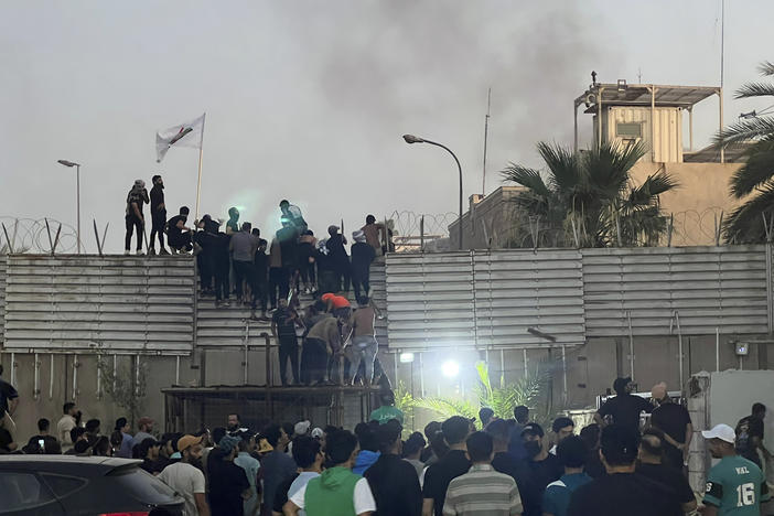 Protesters scale a wall at the Swedish Embassy in Baghdad Thursday. Protesters angered by the planned burning of a copy of the Quran stormed the Embassy early Thursday, breaking into the compound and lighting a small fire.