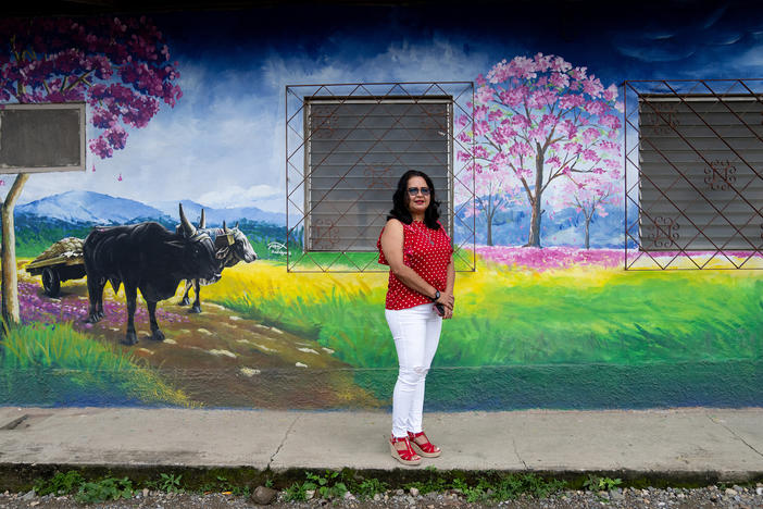 Jacqueline Trejo, mayor of Macuelizo, walks past one of the town's murals. The pink flowering tree that's depicted is the source of the town's name. She wanted to improve the quality of life there but lacked the funds to fulfill her plans.
