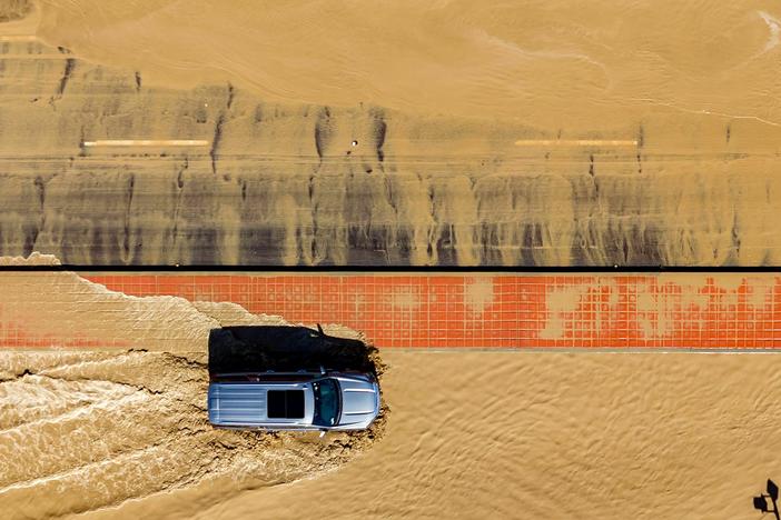 In this aerial picture taken on Aug. 21, a vehicle drives through floodwaters following heavy rains from Tropical Storm Hilary in Thousand Palms, Calif.