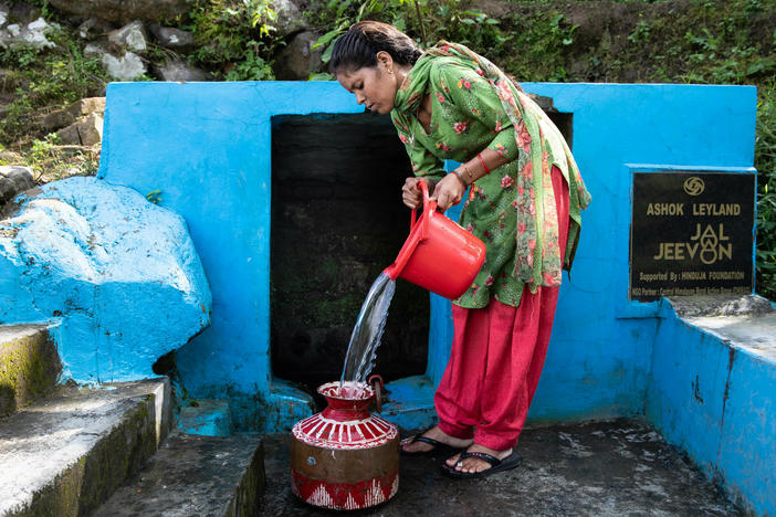 Kiran Joshi fills a copper vessel with water from Ashwanaula, a groundwater spring in the village of Raushil, where she lives with her family