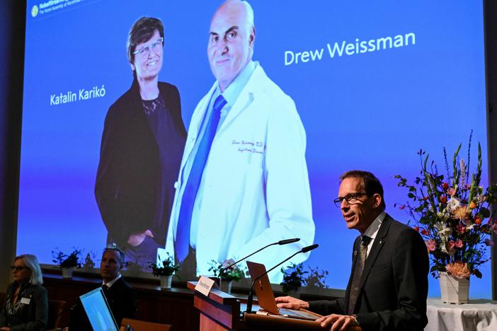 Secretary-General of the Nobel Assembly Thomas Perlmann speaks in front of a picture of Katalin Karikó and Drew Weissman, winners of the 2023 Nobel Prize in Physiology or Medicine, at the Karolinska Institute in Stockholm on Monday.