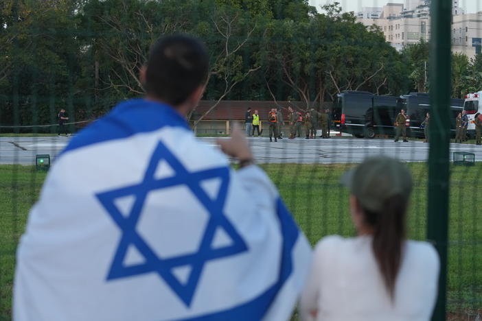 A man wearing an Israeli flag looks toward ambulances outside a hospital in Petah Tikva, Israel, on Nov. 24.