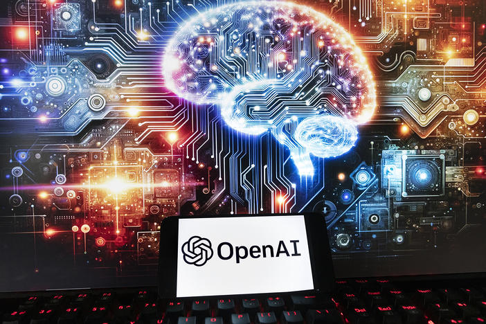 The OpenAI logo is displayed on a cellphone with an image on a computer monitor generated by ChatGPT's Dall-E text-to-image model in Boston on Dec. 8, 2023.