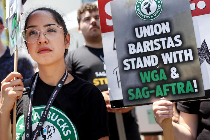 Starbucks workers including barista Kat Ramos stand with striking SAG-AFTRA and Writers Guild of America members on the picket line in solidarity outside Netflix studios on July 28, 2023 in Los Angeles, Calif.
