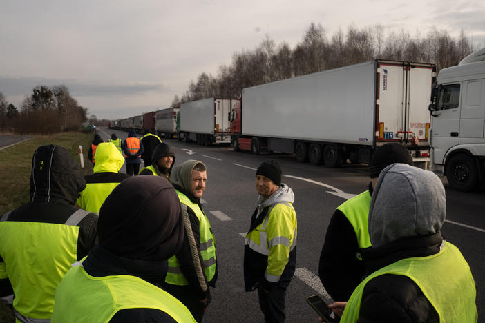 Ukrainian truck drivers stand near a long line of trucks as they wait for days at the Dorohusk border in Poland.