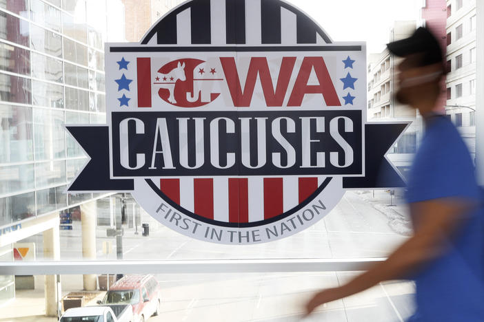 A pedestrian walks past a sign for the Iowa caucuses on a downtown skywalk in Des Moines, Iowa, on Feb. 4, 2020.